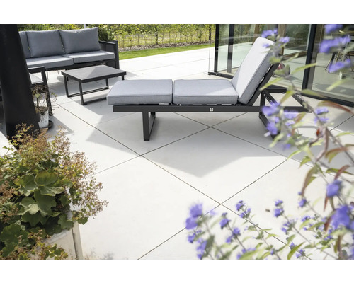 Terrasse avec mobilier de jardin composé d'un canapé, d'une table et d'un transat avec coussins.