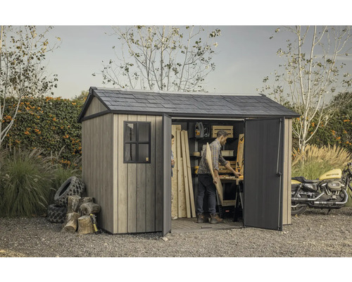 Abri de jardin avec portes ouvertes, établi et une personne travaillant à l'intérieur