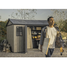 Abri de jardin avec porte ouverte et une personne transportant des outils et du bois