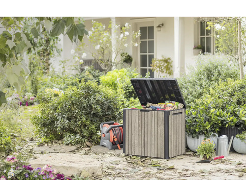 Jardin extérieur avec coffre de rangement, enrouleur de tuyau, arrosoir et plantes