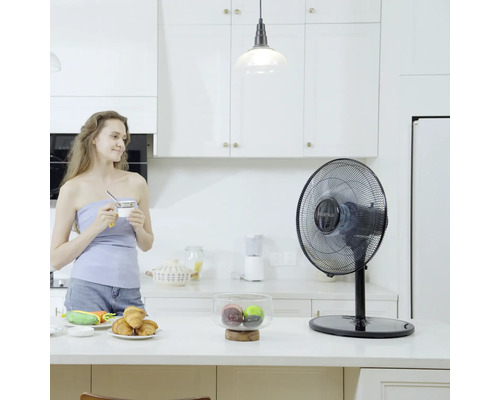 Tischventilator in einer hellen Küche mit einer Frau, die eine Tasse hält