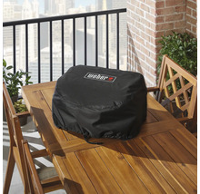 Housse de protection noire pour barbecue Weber sur une table en bois