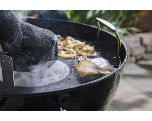 Presse à hamburger en cours d'utilisation sur un grill avec oignons et fromage