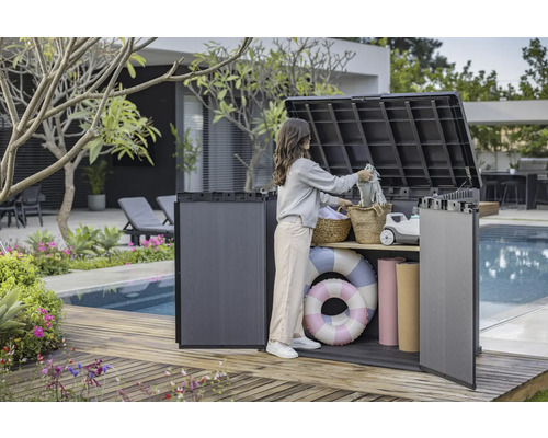 Photo d'une femme utilisant une boîte de rangement extérieure sur une terrasse en bois près d'une piscine pour ranger des objets