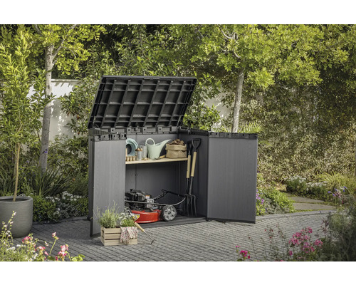 Armoire de jardin avec portes ouvertes et couvercle relevé, remplie d'outils de jardinage et d'une tondeuse à gazon