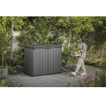 Gartenschrank aus Kunststoff im Garten mit Frau, die einen Korb mit Pflanzen trägt