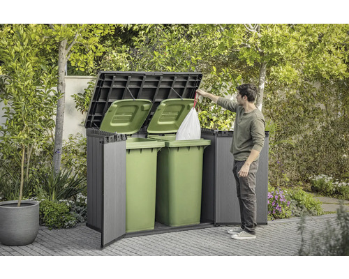 Mülltonnenbox mit Mann, der einen Müllsack hineinwirft, im Garten