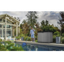Szene eines Mannes, der einen Pool mit einem Kescher reinigt, im Hintergrund ein Poolhaus und ein Gartenschrank