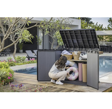 Szene im Garten mit einer Frau, die einen Geräteschrank aus Kunststoff mit zwei Regalböden öffnet, in dem sich Schwimmringe, Handtücher und Körbe befinden.