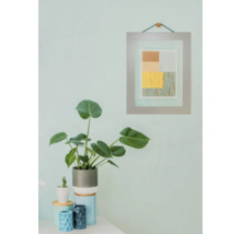 Dekoratives Stillleben mit Zimmerpflanze, Keramikgefäßen und gerahmtem Bild an der Wand.