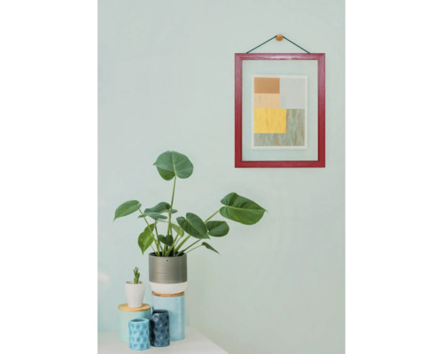 Dekorative Innenraumszene mit Zimmerpflanze und gerahmtem Bild an der Wand