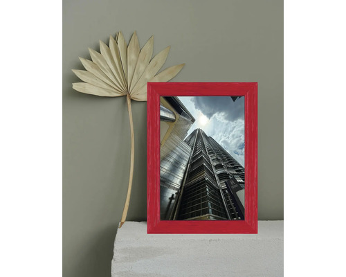 Roter Bilderrahmen mit einem Foto eines Wolkenkratzers und einer getrockneten Blume