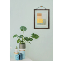 Dekoratives Interieur mit Zimmerpflanze, Bild und kleinen Gefäßen auf einem Tisch.