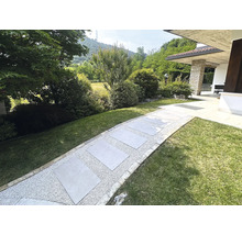 Chemin de jardin avec dalles de pierre et gravier entre les espaces verts