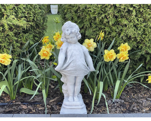 Vue de jardin avec figurine de fille en pierre et jonquilles jaunes