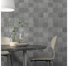 Aménagement mural avec des carreaux carrés gris derrière une table à manger.