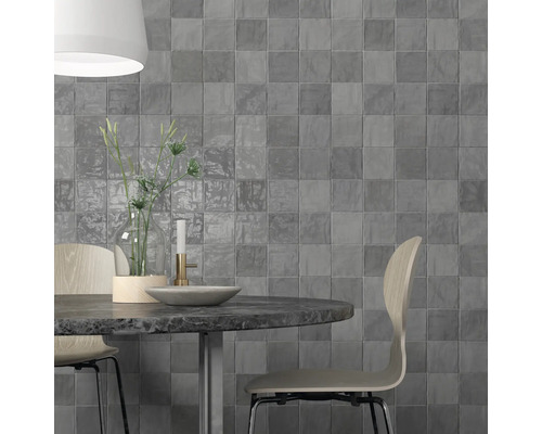 Aménagement mural avec des carreaux carrés gris derrière une table à manger.