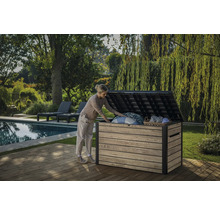 Eine Frau öffnet eine Gartentruhe auf einer Holzterrasse neben einem Pool und Garten.