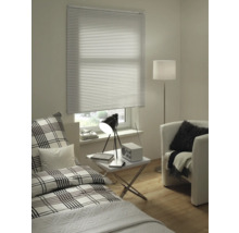 Espace de vie avec lit, fauteuil, lampadaire, table et fenêtre avec stores vénitiens