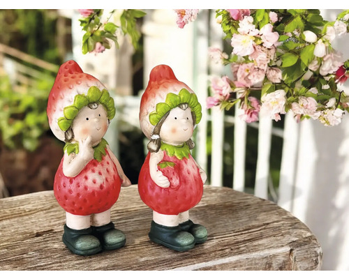 Zwei Erdbeerfiguren als Gartendekoration auf einem Holztisch