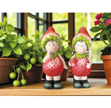 Zwei dekorative Erdbeerfiguren zwischen Pflanzen auf einem Regal