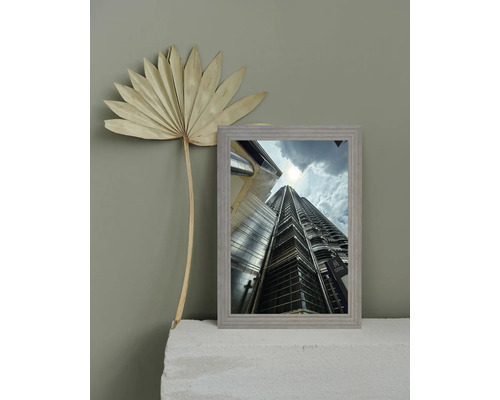Gerahmtes Bild eines Wolkenkratzers mit dekorativem Palmblatt