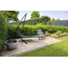 Scène de jardin avec îlot suspendu, chaise longue et foyer sur une surface pavée