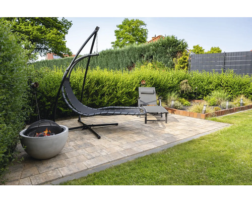 Scène de jardin avec îlot suspendu, chaise longue et foyer sur une surface pavée