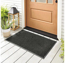 Paillasson gris devant une porte d'entrée sur un porche avec des plantes et un photophore