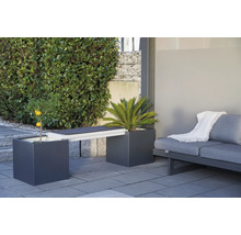 Gartenmöbelanordnung mit Pflanzgefässen, die als Bank dienen, und einem Sofa auf einer Terrasse.