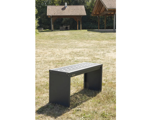 Graue Parkbank mit Lattenrost und Unterstand im Hintergrund