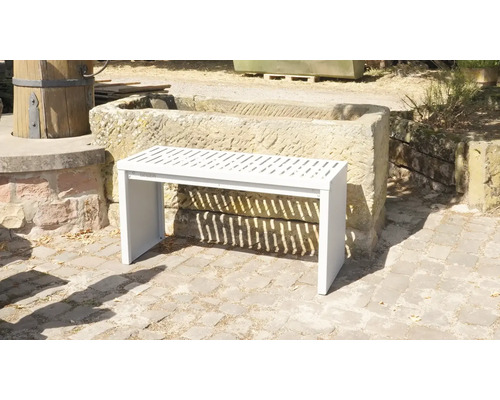 Banc de jardin blanc en métal avec lattes devant un bac en pierre