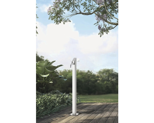 Gartenszene mit einem einzelnen Wasserhahn aus Metall auf einer Holzterrasse