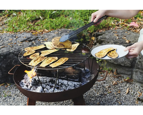 Barbecue avec des tranches d'aubergine et des pinces à barbecue dans le jardin.