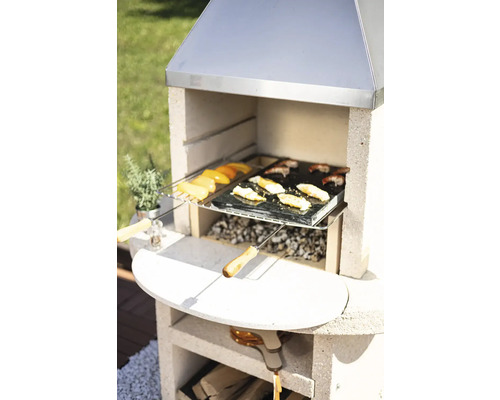 Barbecue en maçonnerie avec des aliments grillés et des accessoires dans le jardin