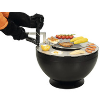 Barbecue sphérique noir avec des aliments grillés et des mains qui l'utilisent