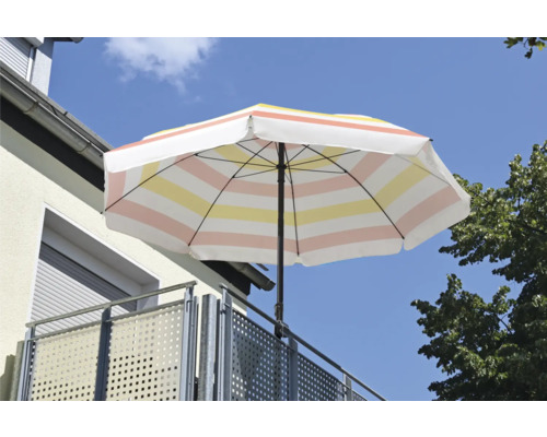 Parasol rayé sur un balcon avec garde-corps métallique.