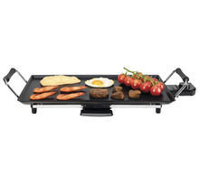 Gril électrique avec divers aliments comme steak, œufs, tomates et crevettes