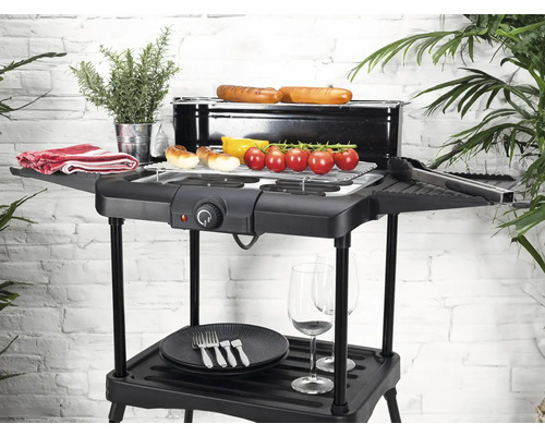 Barbecue électrique avec aliments grillés, vaisselle et plantes sur un balcon