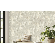 Espace de vie avec un papier peint à motif de plantes, un coussin, un chapeau et une plante d'intérieur.
