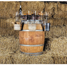 Tonneau à vin avec vin, verres, paniers et accessoires devant une botte de paille