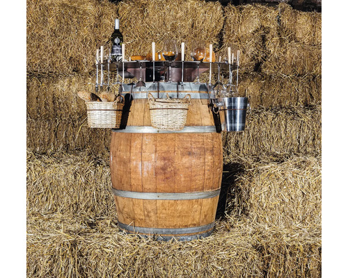 Tonneau à vin avec vin, verres, paniers et accessoires devant une botte de paille
