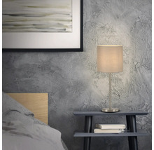 Nachttischlampe mit Stoffschirm auf einem Nachttisch im Schlafzimmer