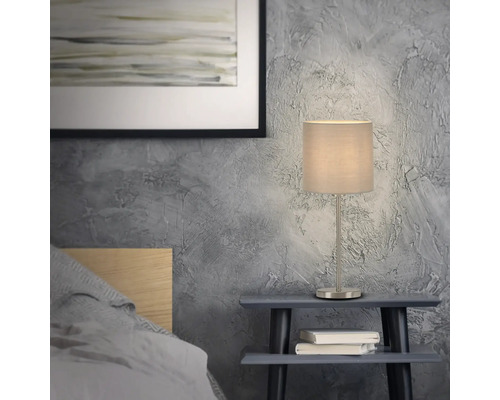 Nachttischlampe mit Stoffschirm auf einem Nachttisch im Schlafzimmer