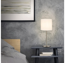 Nachttischszene mit einer Tischlampe auf einem kleinen Tisch neben einem Bett