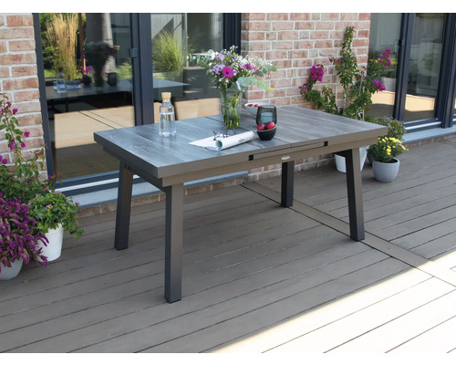 Ausziehbarer Gartentisch auf einer Terrasse mit Blumen und Getränken dekoriert.