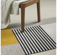 Dekorativer Teppich mit geometrischem Muster unter einem Holzstuhl