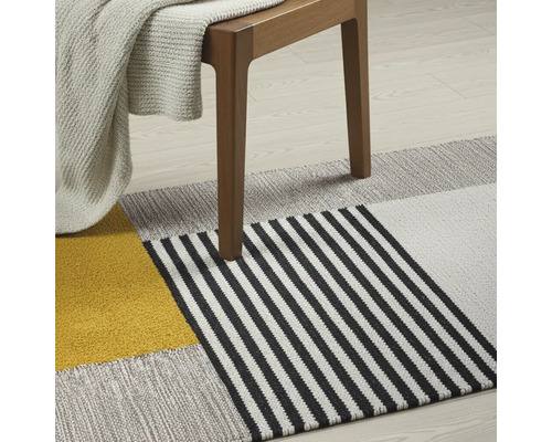 Dekorativer Teppich mit geometrischem Muster unter einem Holzstuhl