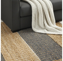 Detailansicht eines gestreiften Teppichs unter einem Sofa mit einer Decke.