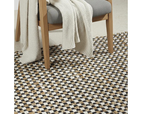 Dekoratives Wohnambiente mit einem Stuhl, einer Decke und einem Teppich im Schachbrettmuster